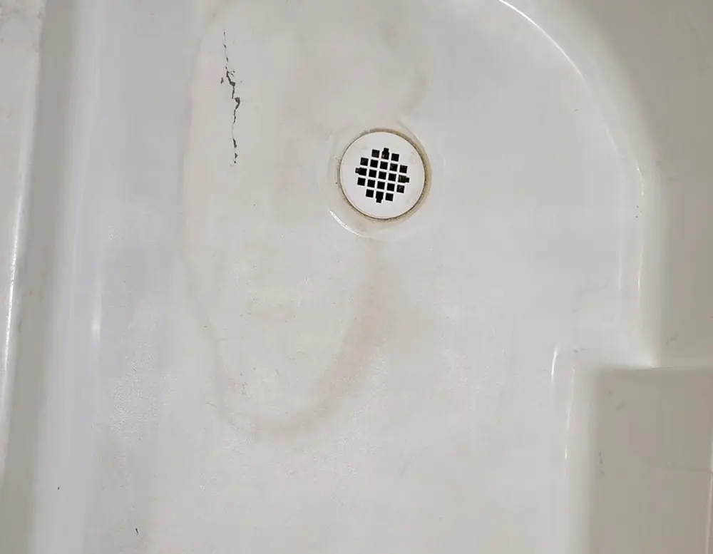 Stained, discolored fiberglass shower pan before refinishing